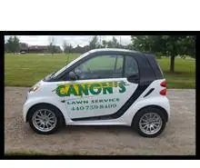 The Canon's Lawn Service Smart car, wrapped in green and gold livery with the business name and phone number on the door