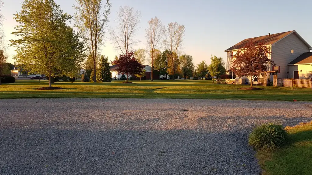 A mown rural Ohio property at golden hour with a gravel drive and mature trees